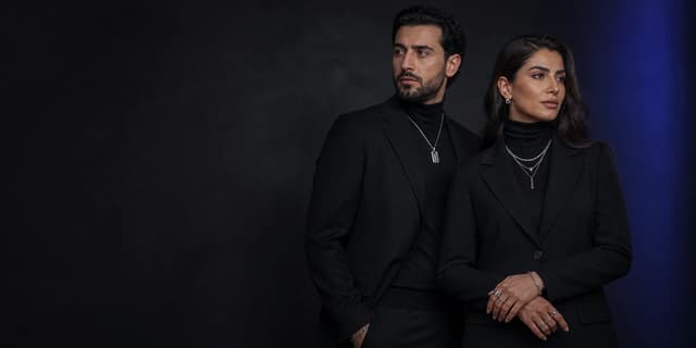Two models in black tailoring wearing contemporary silver jewelry
